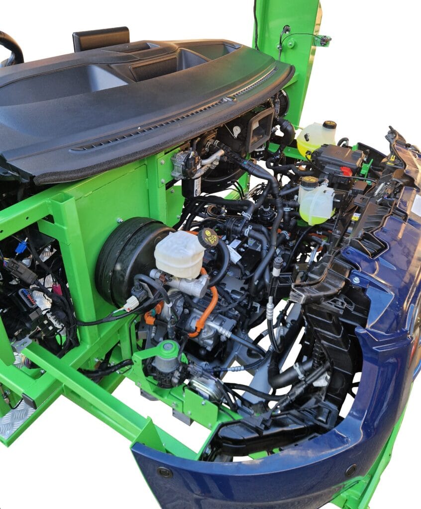 A vehicle's exposed engine bay with components and wiring, showcasing a green support frame and blue exterior panels.