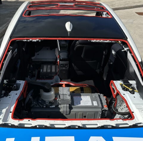 The interior of a car with the engine compartment open.